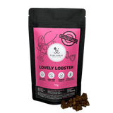 A black pouch of RUBY REESE LOVELY LOBSTER dog treats with a pink label and a ziplock with some treats spilled in front